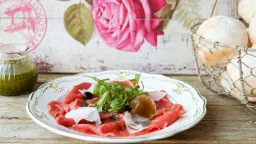 Rundscarpaccio met basilicumolie, parmezaanse kaas, paddenstoelen op olie en notensla