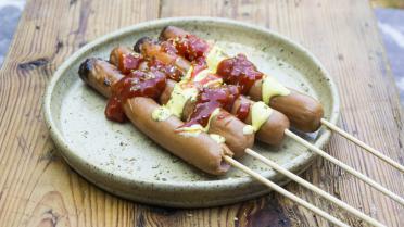 Koken op vuur: hotdogs op een stokje