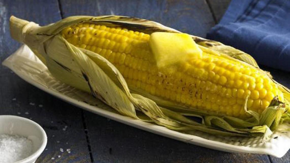 Gegrilde maïskolf met boter op de barbecue